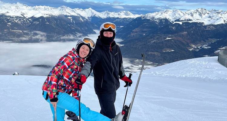 Deux skieurs posant sur une montagne enneigée avec une vue panoramique.