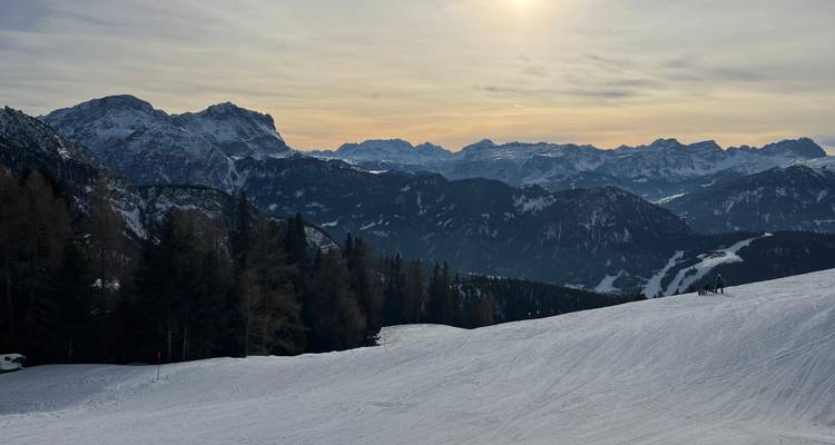 Sommets de montagne vus au coucher du soleil avec des pentes enneigées.
