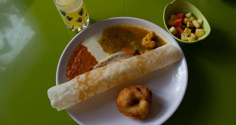 Une assiette de nourriture du sud de l'Inde, comprenant des dosa et des vada, sur une table verte.