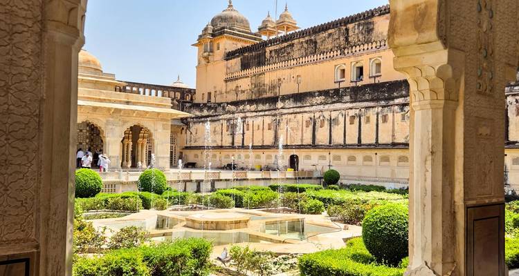 Patio elegante del jardín Mughal con fuentes enmarcadas por columnas ornamentadas y muros del palacio.