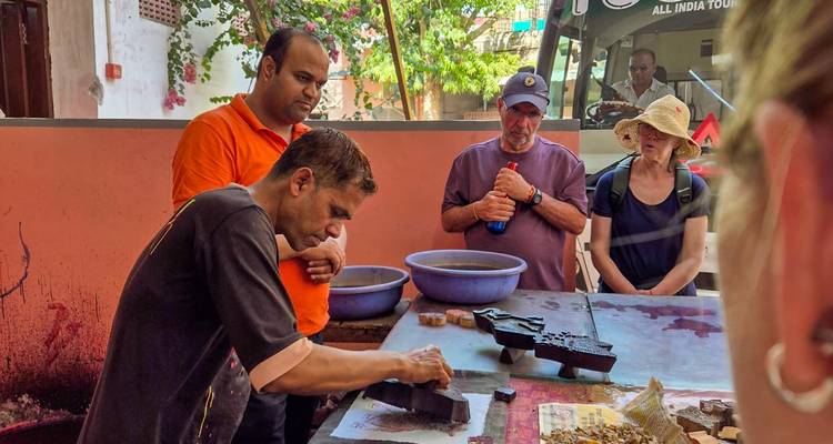 Un artesano demuestra la técnica de impresión en bloque a turistas atentos dentro de un taller.