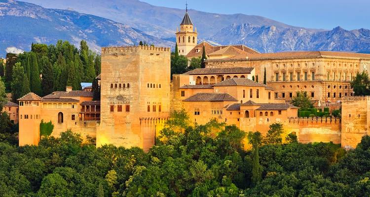 Historic buildings in a lush green valley with mountains.