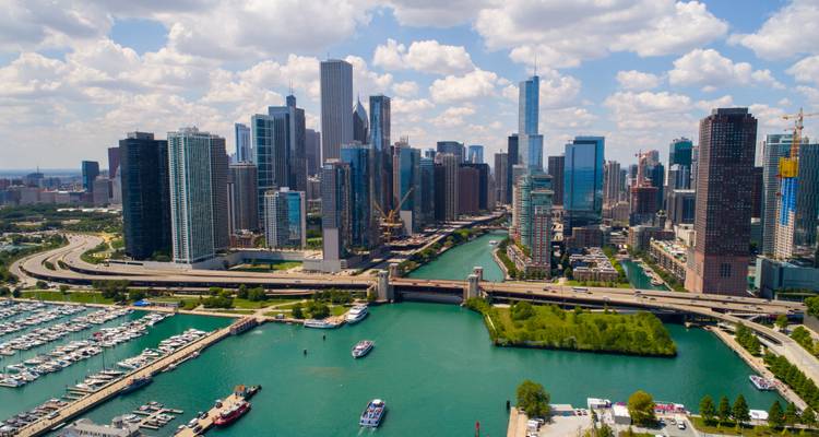 High aerial view of Chicago skyline with towering skyscrapers flanking the green Chicago River and marina on Lake Michigan