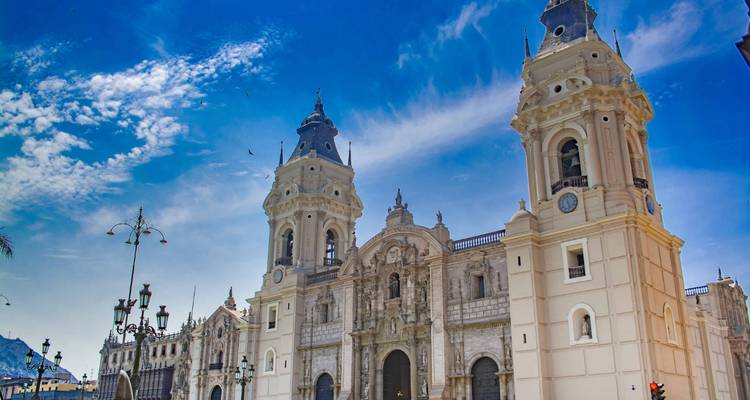 A grand cathedral in downtown Lima with a bright blue sky and clouds.