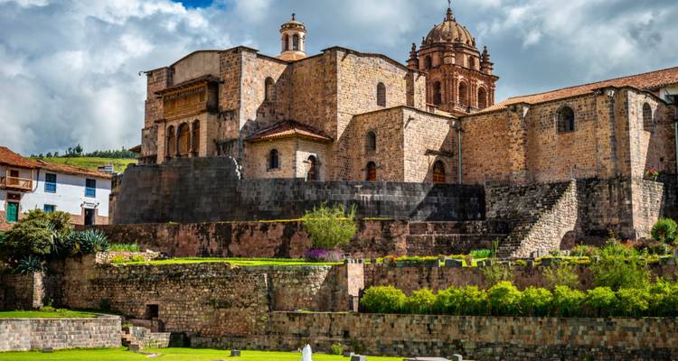 Historical building in Cusco, stone walls and greenery in the foreground.