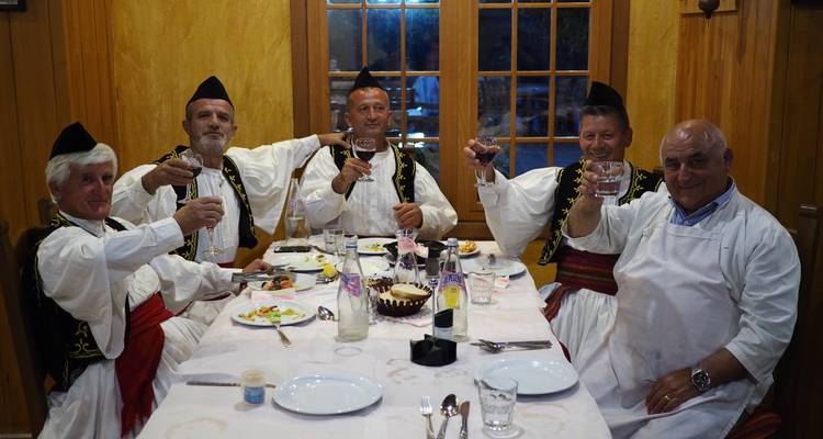 Group of men in traditional clothing at a dining table.