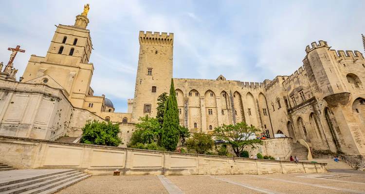 Medieval Palais des Papes with tall towers and golden statue in Avignon