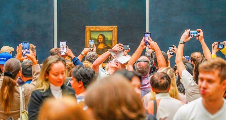 Crowd of visitors photographing the Mona Lisa inside the Louvre Museum