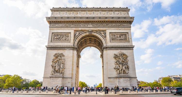 Majestic Arc de Triomphe standing at the center of a busy plaza with many visitors
