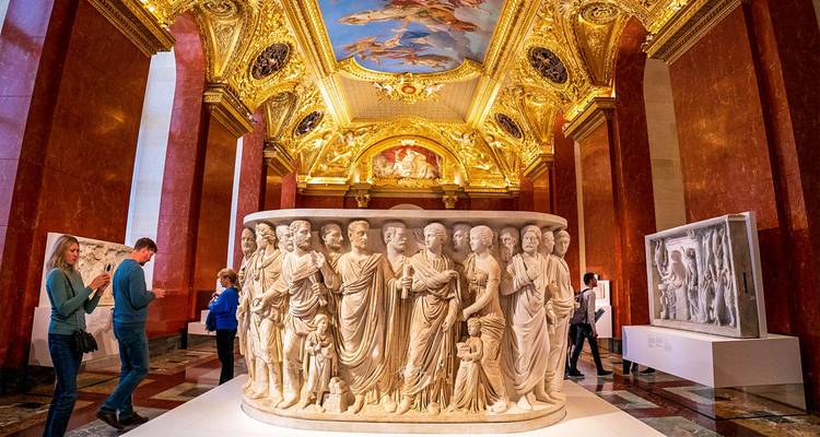 Opulent gallery inside the Louvre with gilded ceiling frescoes and classical sculptures