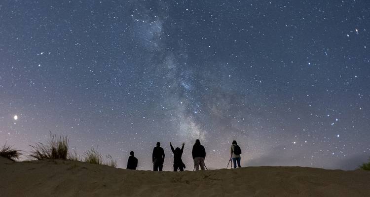 Observación grupal de estrellas en el desierto con una vista clara de la Vía Láctea.