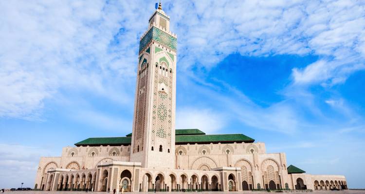 La majestueuse Mosquée Hassan II et son minaret élancé se dressent contre un ciel bleu éclatant.