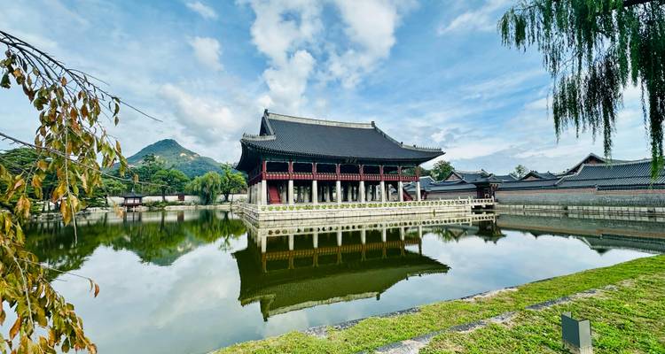 Pavillon Gyeonghoeru se reflétant parfaitement dans l'étang immobile du palais avec les montagnes en arrière-plan et des nuages dispersés