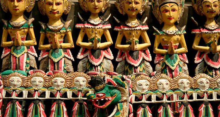 Colorful carved wooden figurines arranged in rows, showcasing traditional Indonesian artistry.