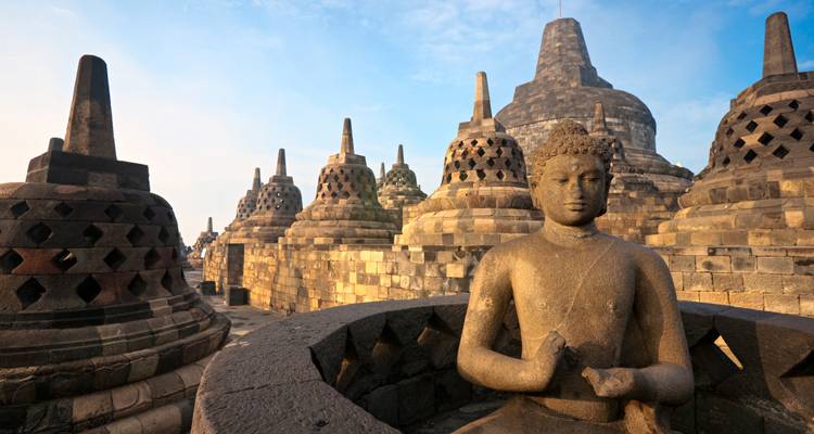 Iconic stupas and Buddha statue of Borobudur temple bathed in soft morning light.