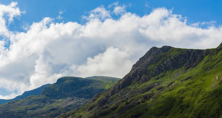 Berggipfel mit üppigem Grün unter blauem Himmel.