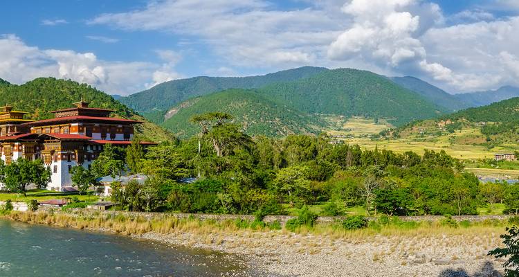 Traditionelle bhutanesische Architektur umgeben von üppigem Grün und Bergen.
