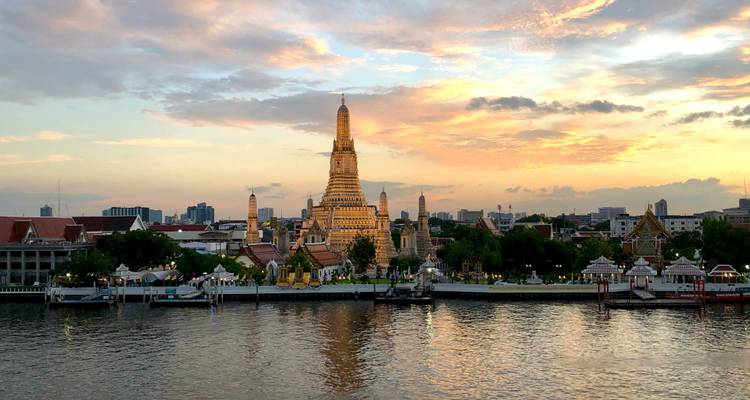 Sunset sky over Wat Arun temple reflecting in the Chao Phraya River.