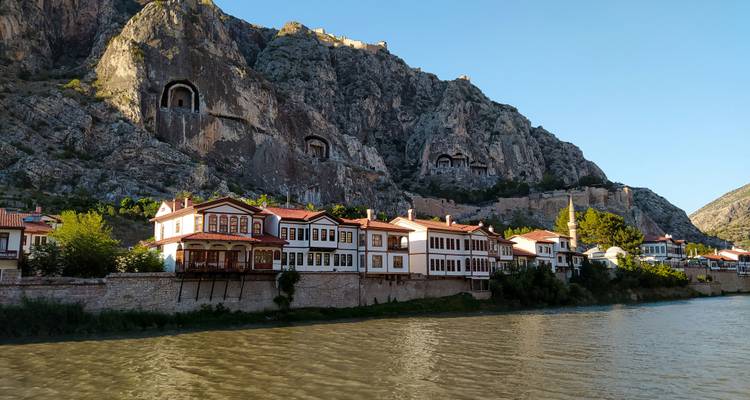 Rivieroeverzicht met traditionele huizen en rotsgraven in Amasya.