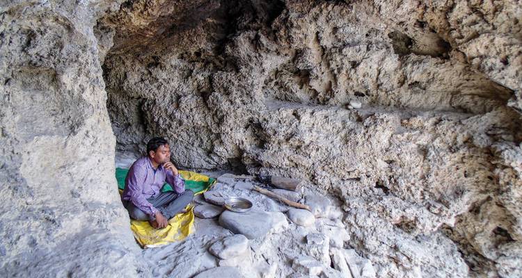 Personne assise dans une petite grotte aux murs de pierre.