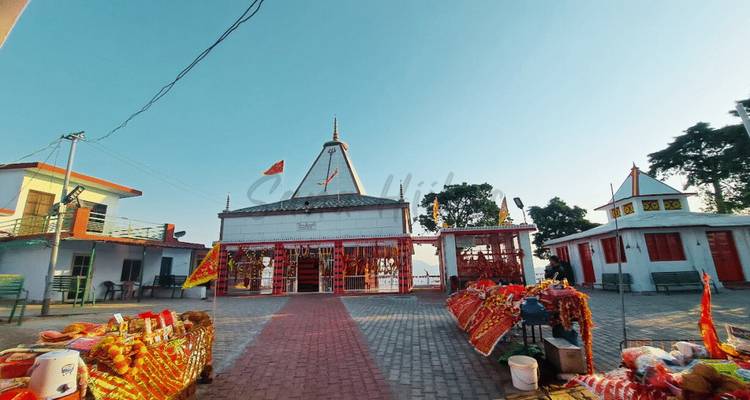 Vue extérieure d'un petit temple avec des offrandes disposées devant.