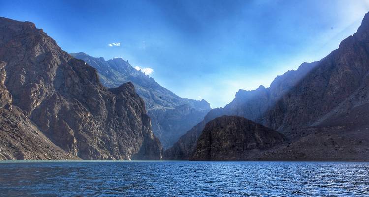 Lac glaciaire bleu profond entouré de hautes falaises rocheuses sous un ciel alpin dégagé