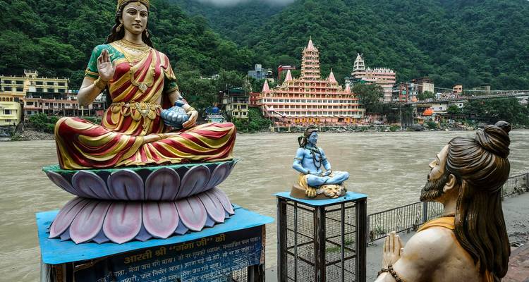 Statuen mit Blick auf einen Fluss mit einem Tempel im Hintergrund.