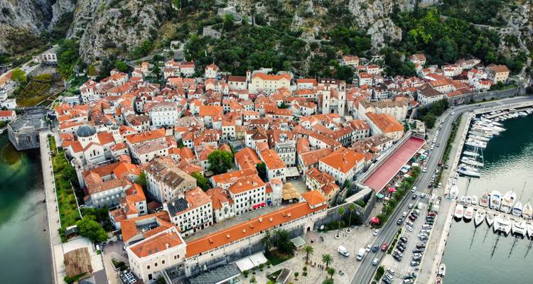 Vue aérienne d'une ville côtière avec des bâtiments aux toits rouges.