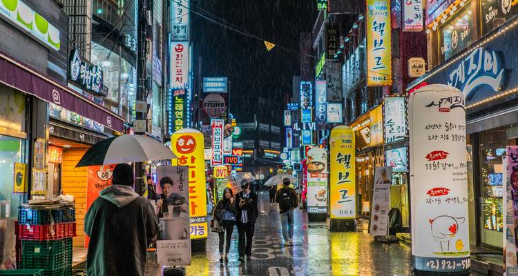 A vibrant street scene with illuminated signs and people walking at night.