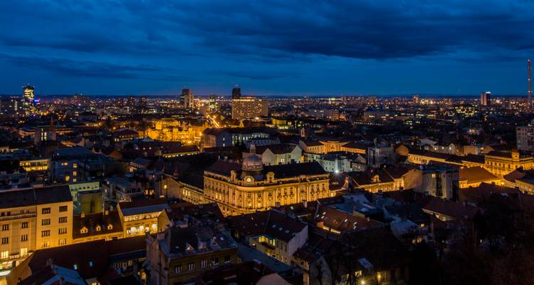 Skyline of a city lit up at night with prominent buildings.