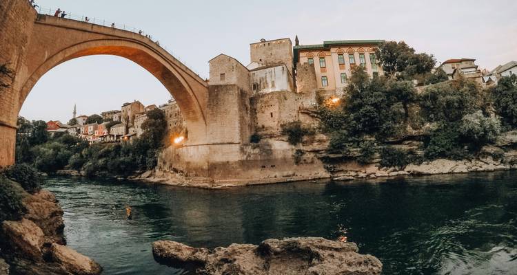 Historic stone bridge over a river in a town with traditional buildings.