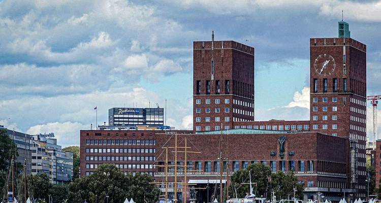 Modern bakstenen gebouw met een klokkentoren, gezien vanaf de waterkant.
