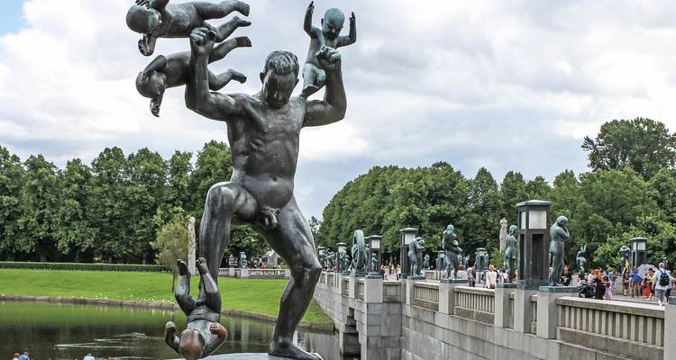 Standbeeld van een man die kinderen jongleert in een park.