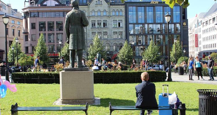 Mensen op een stadsplein met een standbeeld van een man op een voetstuk.