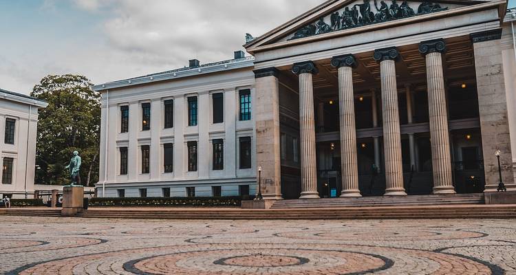 Klassiek gebouw met zuilen en een standbeeld ervoor.