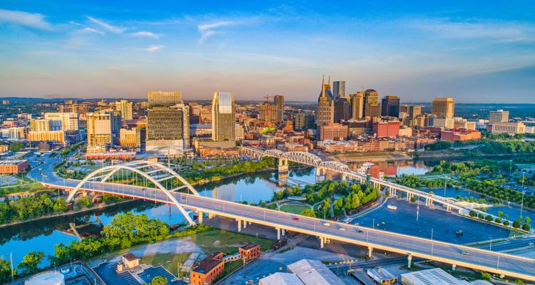 Vue aérienne générale de Nashville montrant les ponts enjambant la rivière et les bâtiments modernes du centre-ville sous un ciel dégagé.