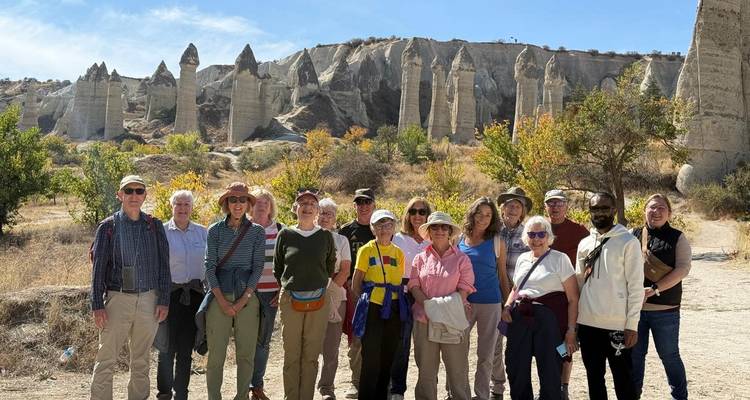 Large tour group posing in front of Cappadocia's “Love Valley” fairy-chimney rock spires.
