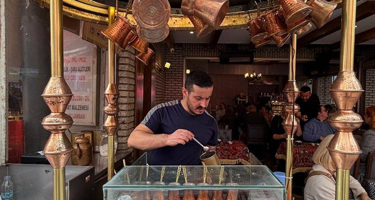 Street vendor preparing traditional Turkish coffee at a copper-decorated stall.