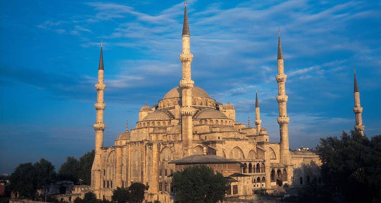 Historic mosque with multiple minarets under a blue sky.