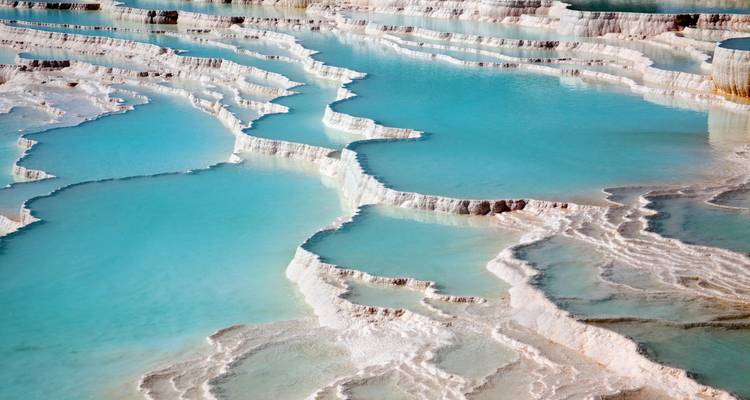 Thermal terraces filled with turquoise water under clear skies.