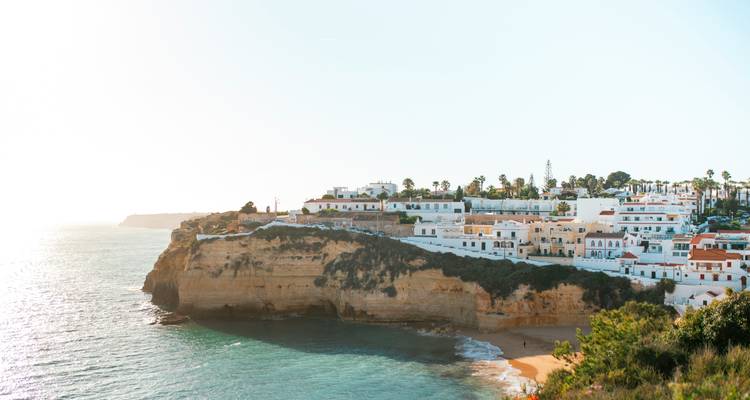 Vue large d'une ville côtière à flanc de falaise avec un ciel bleu dégagé.