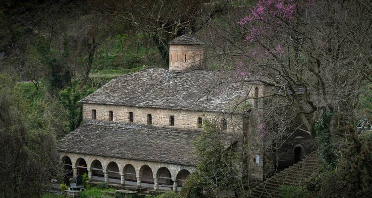 Église historique en pierre entourée d'arbres.
