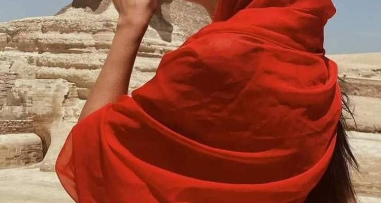 Personne avec un châle rouge posant près du Sphinx.