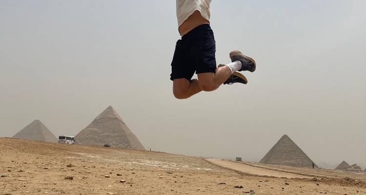 Personne sautant en plein air avec des pyramides en arrière-plan.