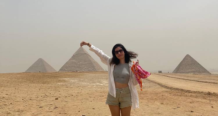 Personne posant avec les pyramides, tenant un foulard coloré.