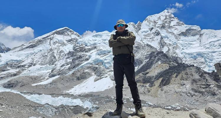 A solitary trekker standing against a backdrop of snow-covered mountains.