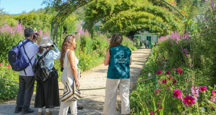 Visitantes paseando por el arco del jardín lleno de flores de Monet en Giverny.
