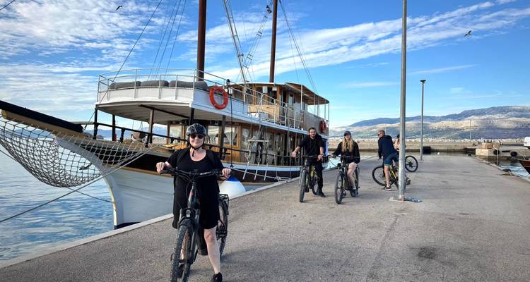 Grupo de ciclistas cerca de un barco atracado junto a un muelle.