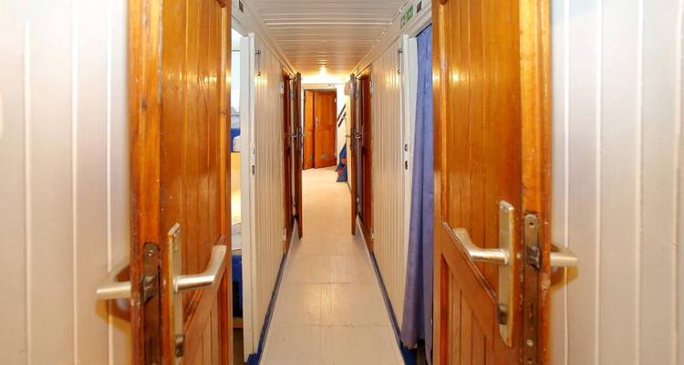 Pasillo estrecho con puertas de madera en un barco.