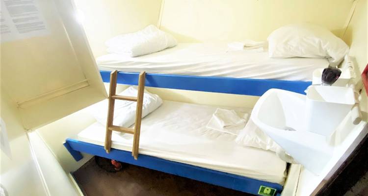 Habitación con literas y un pequeño lavabo en un barco.